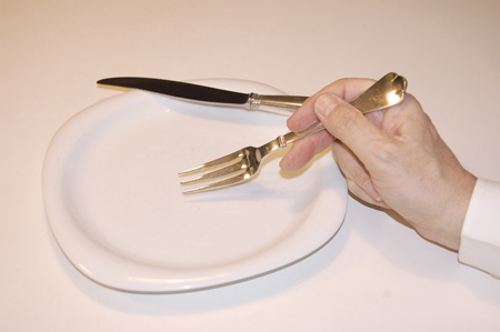eating with a fork while the knife is resting on the plate